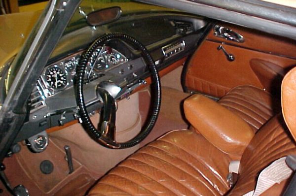 Салон Citroen DS, рулевое колесо с одной спицей, над ним — рычаг переключения передач, внизу видны «палочка» педали газа и «кнопка» педали тормоза, левее — педаль стояночного тормоза.