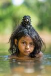 Тамарин на голове у девочки, которая купается в реке Йомибато в Национальном парке Ману в Перу.