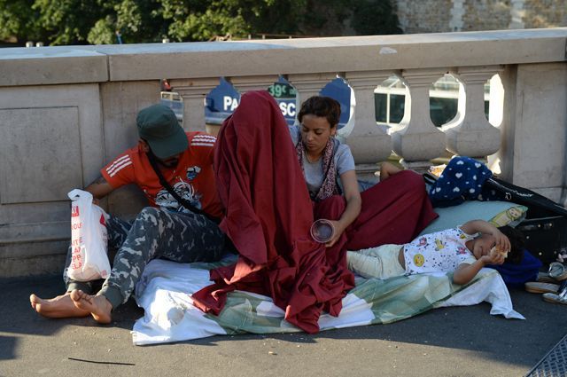 Семья мигрантов на набережной Сены в Париже.