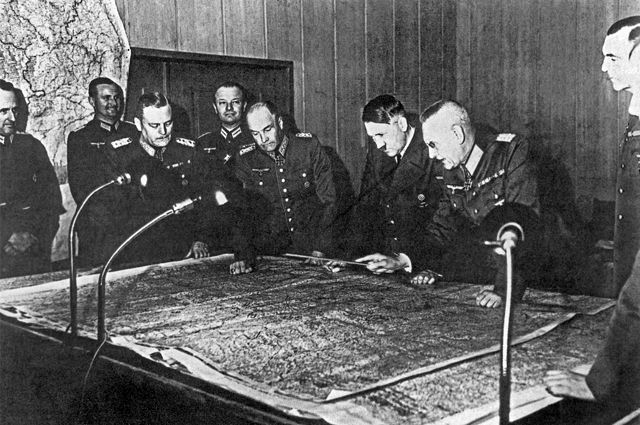 Генерал-фельдмаршал В. Кейтель, генерал-полковник В. фон Браухич, А. Гитлер, генерал-полковник Ф. Гальдер (слева направо на первом плане) около стола с картой во время совещания Генерального штаба.