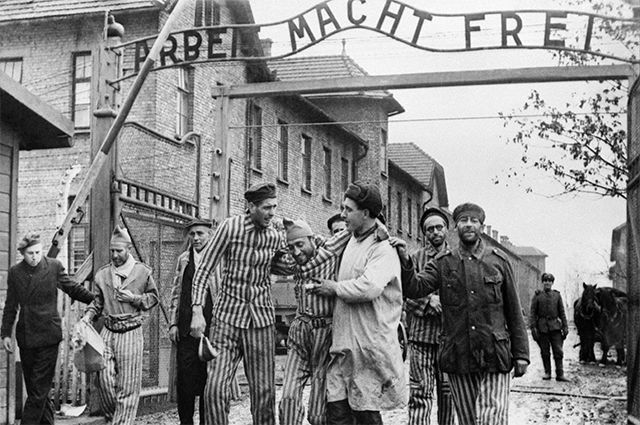 Выжившие в Освенциме покидают лагерь. Над ними – немецкий лозунг «Arbeit macht frei» («Работа делает человека свободным»), февраль 1945 г.