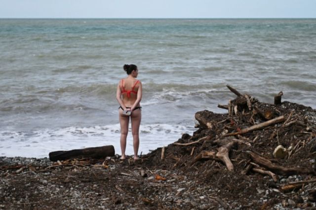 Женщина стоит среди мусора на пляже в поселке Кудепста Хостинского района Сочи.