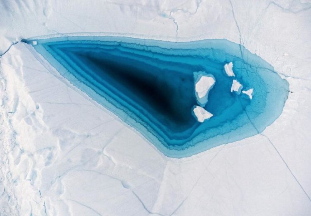 Верхушка одного из айсбергов в Гренландии. В центре снимка — вода, которая видна из-за постепенного таяния льда в результате глобального потепления.