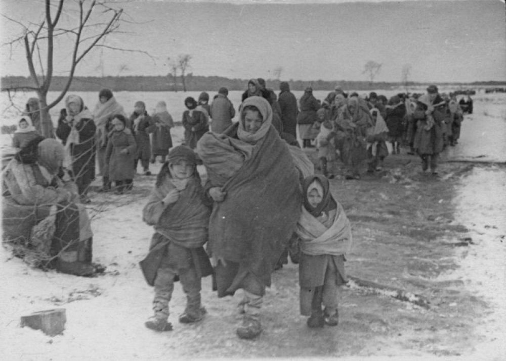 Мария Рычанкова (из деревни Виричев) с тремя детьми, освобожденные из концлагеря, на пути в поселок Озаричи. Слева - Иван (1937 г.р.), на руках у Марии - Феня, справа - Аня. Двухлетняя Феня (умерла 23 марта) и четырехлетняя Аня (умерла 29 марта) умерли от последствий заключения, 1944 год.