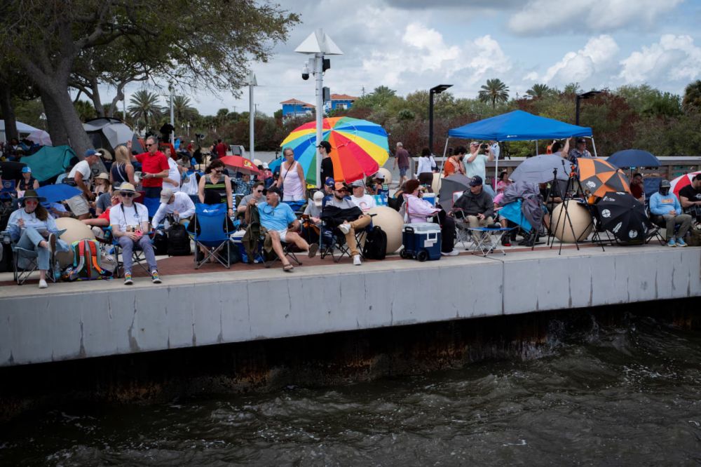 Люди собираются в парке, чтобы смотреть на запуск ракеты. 